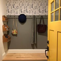 a yellow door is open and there are purses hanging on the wall next to it