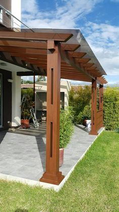 a wooden pergola sitting on top of a lush green field next to a building