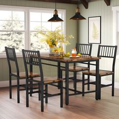 a dining table with four chairs and a vase filled with flowers on top of it