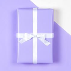 a purple gift box with a white ribbon