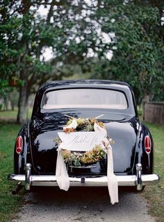 an old black car with a wreath on the back