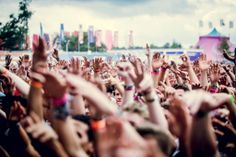 a crowd of people with their hands up in the air at a music festival or concert