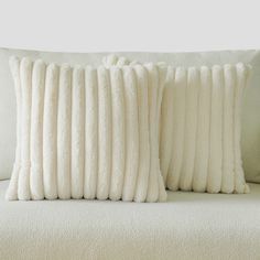 two white pillows sitting on top of a couch