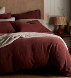 a bed with red sheets and pillows in a bedroom