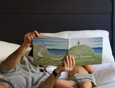 a man laying in bed reading a book