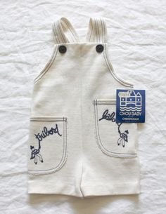 "FRENCH VINTAGE 70's, very cute short overalls / summer jumpsuit, cream textured jersey ( polyester and acrylic ), \" bâbord and tribord\" embroideries on pockets,navy blue overstitchings and buttons. Brand \" Chou Baby \". Size 2 years Vintage condition level 5, new old stock ( washed once ) We assess the condition of our vintage items on a scale from 0 to 5. Level 5 corresponds to an almost new vintage condition. Any defects are systematically reported. Even though in very good condition, vint Playful White Cotton Jumpsuits And Rompers, Cream Jumpsuits And Rompers With Pockets For Summer, Beige Cotton Overalls For Summer, Cream Cotton Jumpsuits And Rompers With Pockets, Beige Cotton Overalls, Sleeveless White Cotton Overalls, Cute White Cotton Overalls, Vintage Bib Front Overalls For Summer, Vintage White Jumpsuits And Rompers For Spring