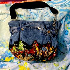 a handbag made out of jeans and other fabric material on a bed with a colorful comforter