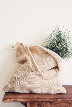 a crocheted bag sitting on top of a wooden table next to a plant