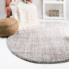 a living room with a round rug, chair and bookshelf on the wall