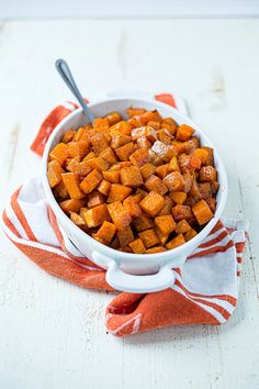 a white bowl filled with sweet potatoes on top of a red and white towel