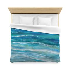 a bed with blue water and white pillows on top of it, next to a wooden headboard