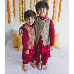 two young boys standing next to each other on a bed