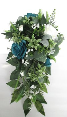 a bouquet of flowers and greenery on a white tablecloth with blue roses, eucalyptus leaves and baby's breath