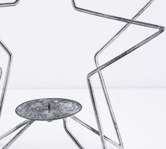 an artistic metal sculpture sitting on top of a white floor next to a small table