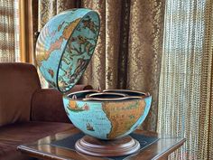 a globe sitting on top of a table next to a brown chair in front of a window