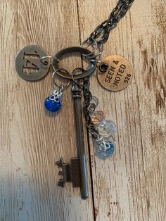 "A lovely set of charms hang off of a vintage style skeleton key. Each of the items and it's jump rings are in a variety of metal finishes. They hang off of a 13\" black stainless, box-like chain which could be adjusted if you would like. The variety of charms include two round tags; one with the sentiment, \"Seen and Noted\" engraved into it and an openwork number \"14\". The other charms are beads; two of which dangle from their own piece of chain and one which hangs on its own. Remember, this is a handmade item and can be quite delicate. This is not a toy. This is not intended for children; it is made from small parts and poses a safety hazard. Please use it only for its intended purpose and under strict adult supervision. Please examine all of the photos and be sure that this is the it Metal Key Pendant Jewelry, Key Pendant Jewelry In Metal, Metal Key Necklace Perfect As Gift, Metal Jewelry With Keys For Gifts, Vintage Metal Jewelry With Two Keys, Vintage Personalized Metal Charm Necklace, Key Detail Metal Jewelry As A Gift, Vintage Metal Jewelry With Keys Detail, Vintage Metal Jewelry With Keys