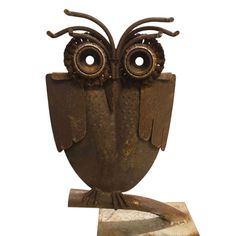 an owl statue sitting on top of a piece of wood next to a white background