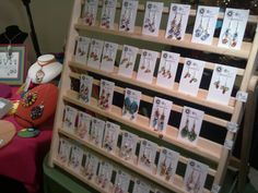 there are many cards on display in the store with price tags attached to them and hanging from wooden racks