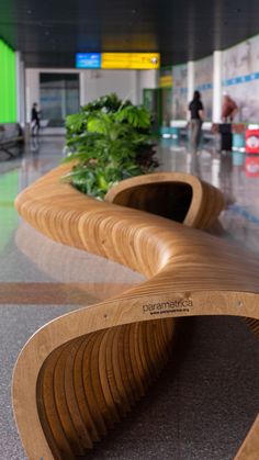 curved wooden bench in an airport terminal with plants growing out of the seats and people walking by