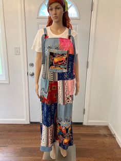 a mannequin wearing a multicolored patchwork dress and headband stands in front of a door