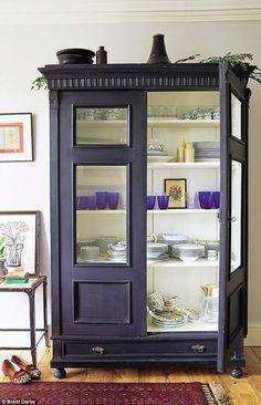 an old china cabinet with glass doors and shelves filled with dishes, plates and glasses