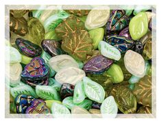 many different colored glass beads with leaves on them, all in various shapes and sizes