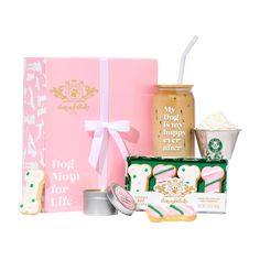 a pink box filled with cookies next to other treats and confection items on a white background