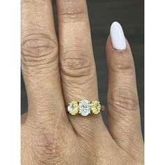 a woman's hand with three yellow and white diamonds on her finger, next to an engagement ring