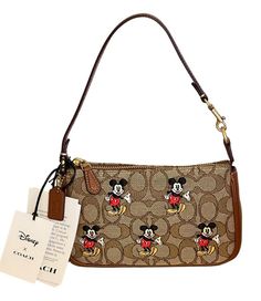 New with Tags Comes with Coach gift box, Tissue paper and sticker Bag wasn’t displayed and comes in original manufacturer packaging This Coach X Disney Nolita 19 wristlet, model CN507, is a stylish accessory that will add a touch of fun to any outfit. The exterior features a brass/khaki/redwood multi-colored signature jacquard pattern, with a cute Mickey Mouse character accent. The wristlet has a zip closure and a convenient wrist strap drop of 6.25". Inside, there are credit card slots for adde Coach X Disney, Nolita 19, Mickey Mouse Characters, Mouse Character, Cute Mickey Mouse, Dream Bag, Disney World Outfits, Tan Shoulder Bag, Coach Gift