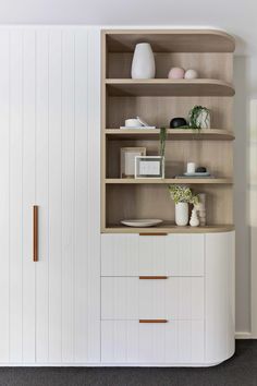 a white bookcase with wooden shelves and drawers