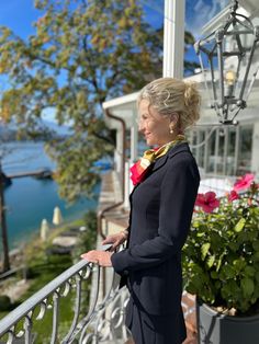 a woman standing on a balcony next to flowers