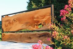 a bed frame made out of wood and metal with pink flowers in the foreground