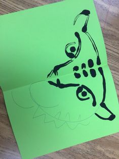 a green piece of paper with a drawing of a person on it and a black outline