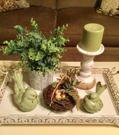 a tray that has some plants in it on top of a table next to a candle