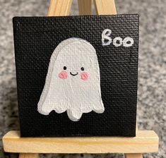 a small wooden easel with a ghost painted on it