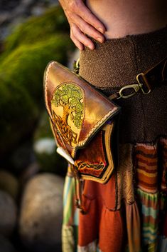 a person wearing a skirt and belt with a purse on their back, in front of some rocks