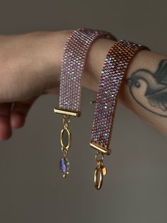 a woman's arm with two bracelets on it and a bird charm hanging from the wrist