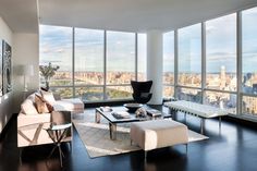 a living room filled with furniture and large windows overlooking the cityscape in new york