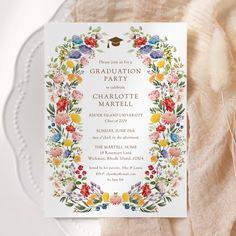 a floral graduation party card on top of a white plate with an orange and yellow ribbon