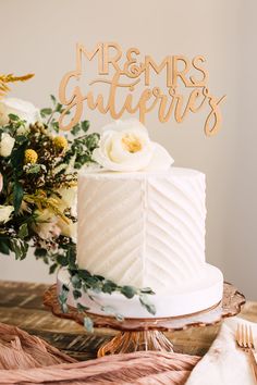 a white wedding cake sitting on top of a table next to a vase with flowers