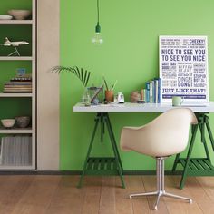 a green room with a white desk and chair next to bookshelves on the wall