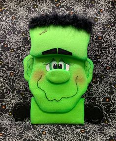 a green stuffed toy with black hair and eyes