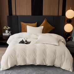 a bed with white comforter and pillows in a hotel room next to a chair