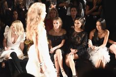 several women sitting on the front row at a fashion show, all dressed in black and white