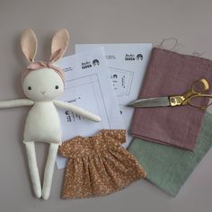 the doll is next to some fabric and scissors