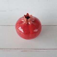 a small red vase sitting on top of a white table next to a wooden floor