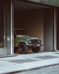 a green jeep parked in front of a building