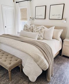 a bed with white sheets and pillows in a bedroom next to a chandelier