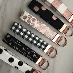 four different color and pattern belts with metal buckles on each one, all lined up against a white marble surface