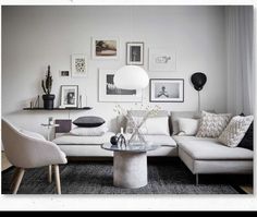 a living room filled with white furniture and pictures on the wall above it's coffee table